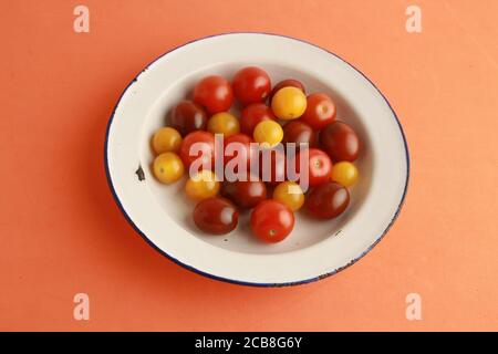 Nahaufnahme von drei Arten von Kirschtomaten auf einem Orangefarbene Oberfläche Stockfoto