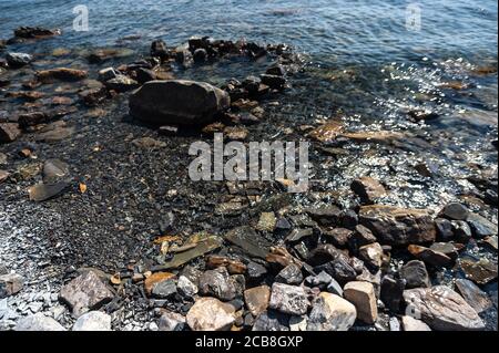 Ein felsiger Strand neben einem Gewässer Stockfoto