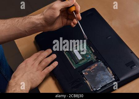 Mann mit Schraubendreher und Reparatur eines defekten Laptop für Kunden, Nahaufnahme Foto. Beruf, Beruf, Hobby, Freizeit Stockfoto