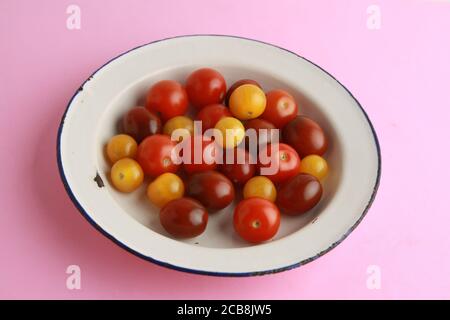 Nahaufnahme von drei Arten von Kirschtomaten auf einem Rosa Oberfläche Stockfoto