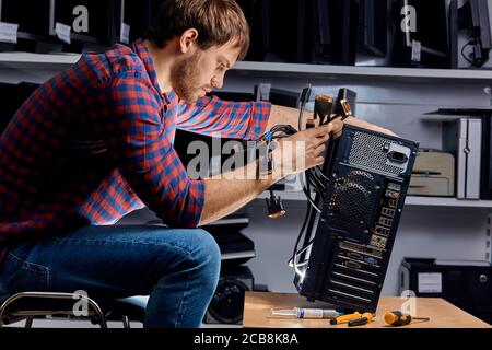 Junger Techniker, der die Kabel der Systemeinheit ersetzt, Nahaufnahme Seitenansicht Stockfoto