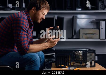 Talentierter Mann lernen, kaputte PC zu reparieren, Nahaufnahme Seitenansicht Foto Stockfoto