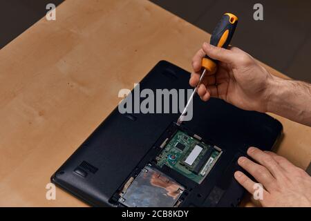 Attraktive hart arbeitenden Kerl Demontage Laptop mit Schraubendreher, Nahaufnahme, Nahaufnahme Foto. Business-und Computer-Reparatur-Konzepte Stockfoto