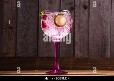Nahaufnahme von Gin und Tonic mit Eis und Himbeeren gegen Ein Holzhintergrund Stockfoto