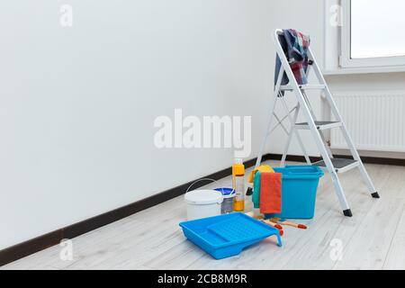 Leiter und Satz von Werkzeugen für die Reparatur auf dem Boden in leeren weißen Raum, für die Renovierung vorbereitet. Stockfoto