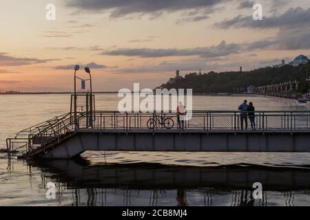 Chabarowsk, Russland - 18. August 2019. Sonnenuntergang auf dem Amur. Der Damm, der Pier und die Menschen, die darauf stehen, sind sichtbar. Stockfoto