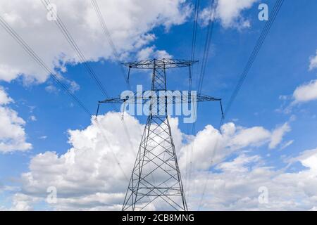 Ein großer Metall-Strompylon oder Übertragungsturm gegen ein Blauer Himmel mit Wolken Stockfoto