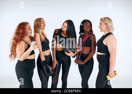 Lächelnde Frauen in schwarzen sportlichen Kleidern lachen, einander anschauen, einen gesunden Lebensstil fördern, Menschen Beziehung. Stockfoto