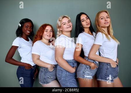 Portrait von fünf schönen Frauen in Jeans stehen isoliert zusammen Auf grauem Hintergrund Stockfoto