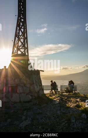 Romantische Paare, die sich während des Sonnenuntergangs über einer majestätischen Landschaft umarmen. Stockfoto