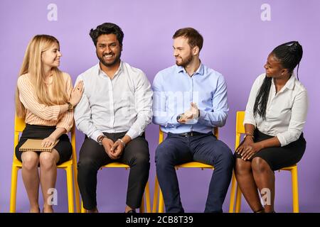 Multinationales Team lächelt fröhlich und gratuliert ihrem Kollegen und wartet Für Vorstellungsgespräche Stockfoto