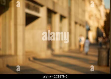Verwischen Sie die Menschen, die in der sonnigen Straße der Stadt spazieren Stockfoto