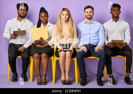 Gruppe von multinationalen jungen Menschen sitzen zusammen und schauen hinein Kamera wartet auf Bewerbungsgespräch Stockfoto