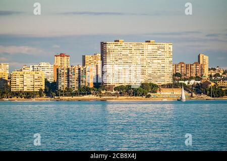 Skyline von San Juan, Alicante, in Spanien, an einem sonnigen Nachmittag mit den 70er Wohnblocks, die sich auf dem Meer spiegeln. Stockfoto