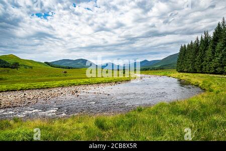 Schottische Highlands Sommerlandschaft. Grünes Tal in schottischen Highlands in der Nähe der Brücke von Orchy mit Abhainn Shira Fluss und Hügeln am Horizont. Stockfoto