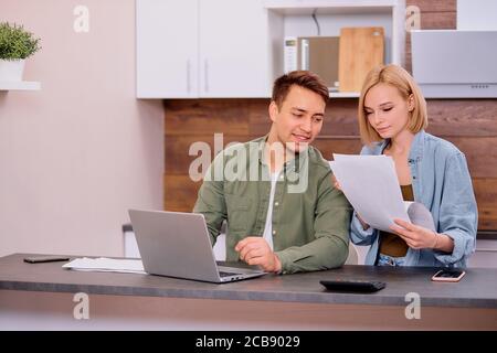 Paar mit Papierdokumenten diskutieren über Geldscheine in der Küche zu Hause, die Familie diskutiert über Budgetausgaben, ein Mann und eine Frau, die Finan lösen Stockfoto