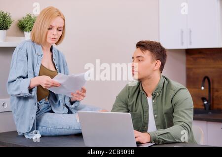 Ehepartner sitzen mit modernen Laptop und Dokumente, Analyse Papierkram und Hauswirtschaftsrechnungen, junges Paar betrachten Papiere Verwaltung Finanzen und expe Stockfoto