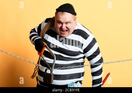 Mann mit weit offenem Mund versucht, in das Haus zu brechen. Isolierte gelbe Hintergrund. studio erschossen. Stockfoto