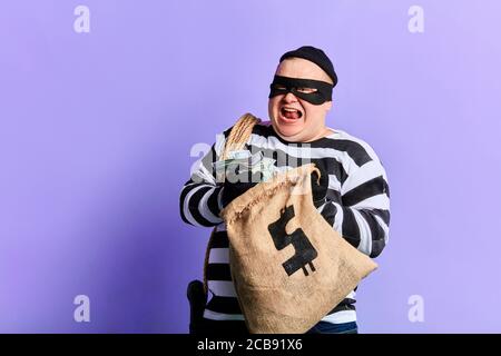 Rich Gefangener in gestreiften Uniform drückt seine positive Emotion und Glück. Isoliert blauen Hintergrund Stockfoto