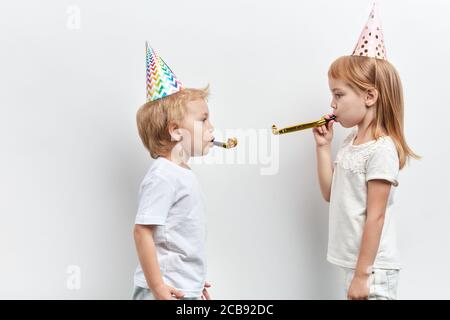 Lustige Sohn und Tochter weht in einem Party-Horn, havinf Spaß, isoliert weißen Hintergrund, Lifestyle-Spiel, Unterhaltung Stockfoto