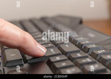 Drücken Sie mit dem Finger auf die ENTER-Taste auf einer schwarzen Computertastatur Stockfoto