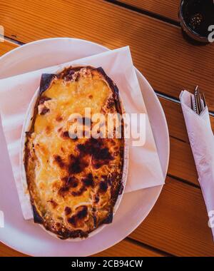 Lasagne Bolognese serviert in einem Restaurant in einer traditionellen Keramikschale mit einem Glas Wein. Restaurant an der Küste der adria, Blick von oben nach unten Stockfoto