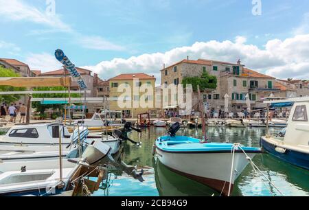 Schöne Aussicht auf die Küste von einer kleinen Stadt Postira auf der Insel Brac in Kroatien. Alte Holzboote dockten im alten Hafen an, hell und farbenfroh Stockfoto