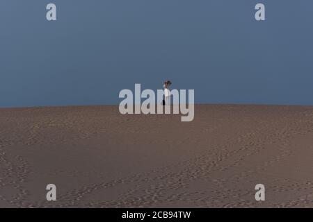 Low-Angle-Aufnahme einer Frau, die in den Dünen von Corralejo auf den Kanarischen Inseln, Spanien, läuft Stockfoto