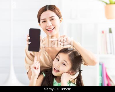 Glückliche Mutter und Tochter zeigen das Handy Stockfoto