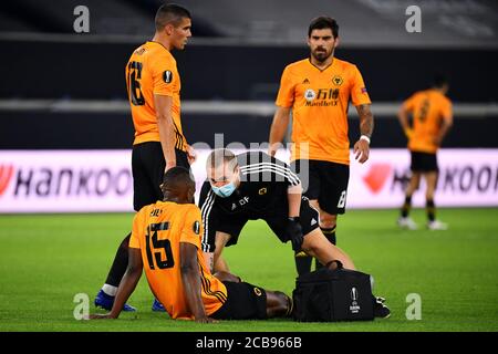 (200812) -- DUISBURG, 12. August 2020 (Xinhua) -- Willy Boly (unten) von Wolverhampton Wanderers wird während des UEFA Europa League Viertelfinales zwischen Wolverhampton Wanderers und dem Sevilla FC in Duisburg, Deutschland, 11. August 2020, medizinisch behandelt. NUR FÜR REDAKTIONELLE ZWECKE. NICHT ZUM VERKAUF FÜR MARKETING- ODER WERBEKAMPAGNEN. (Stuart Franklin/UEFA/Getty/Handout über Xinhua) Stockfoto