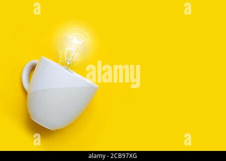 Glühlampe in weißer Tasse auf gelbem Hintergrund. Ideen und kreatives Denkkonzept. Speicherplatz kopieren Stockfoto