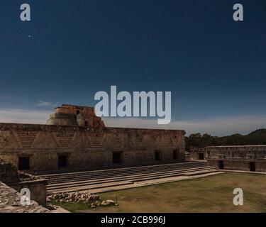 Das östliche Gebäude des Nunnery Quadrangle und die Pyramide des Magiers hinter ihm werden durch den Mond in den prähispanischen Mayaruinen von Uxmal, mir beleuchtet Stockfoto