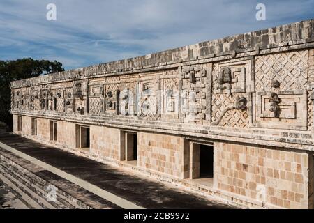 Der Fries des Westgebäudes im Nonnenkomplex in den prähispanischen Maya-Ruinen von Uxmal, Mexiko, ist mit geschnitzten Steinfiguren, geomet, verziert Stockfoto