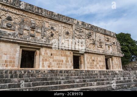 Der Fries des Westgebäudes im Nonnenkomplex in den prähispanischen Maya-Ruinen von Uxmal, Mexiko, ist mit geschnitzten Steinfiguren, geomet, verziert Stockfoto