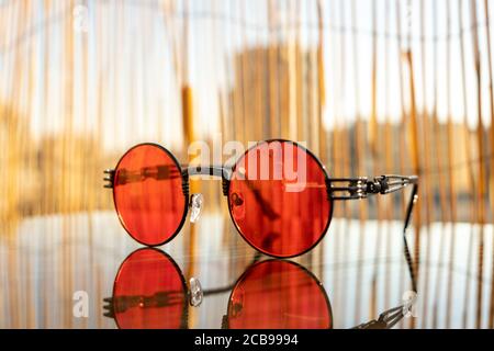 Sonnenbrillen Steampunk mit roter runder Linse Bleiben Sie an einem sonnigen Tag im Sommer auf dem Tisch. Selektiver Fokus Stockfoto