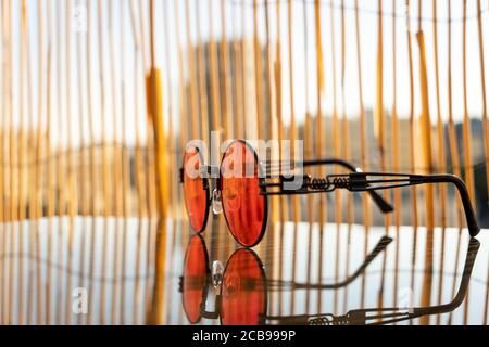 Sonnenbrillen Steampunk mit roter runder Linse Bleiben Sie an einem sonnigen Tag im Sommer auf dem Tisch. Selektiver Fokus Stockfoto