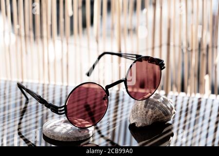 Sonnenbrillen Steampunk mit roter runder Linse Bleiben Sie an einem sonnigen Tag im Sommer auf dem Tisch. Selektiver Fokus Stockfoto