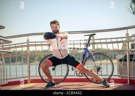 Männlicher Athlet beim Warm-up in der Nähe des Fahrrads Stockfoto