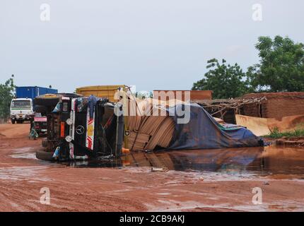 Ein LKW aus Sperrholz kippte auf einer schlammigen afrikanischen Straße Stockfoto