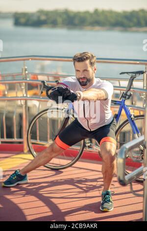 Zufriedene sportliche Mann trainieren im Freien in der Nähe von Fahrrad Stockfoto