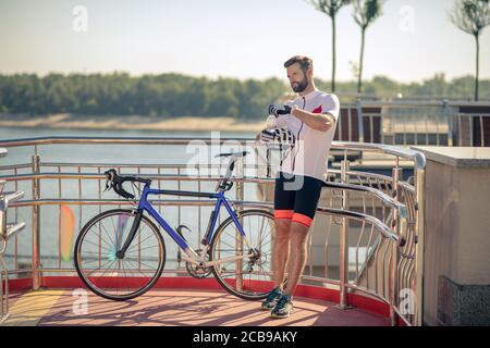 Ruhender Radfahrer steht mit Wasser in der Nähe des Fahrrads Stockfoto