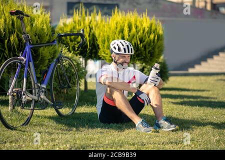 Radfahrer sitzen auf dem Gras in der Nähe des Fahrrads Stockfoto