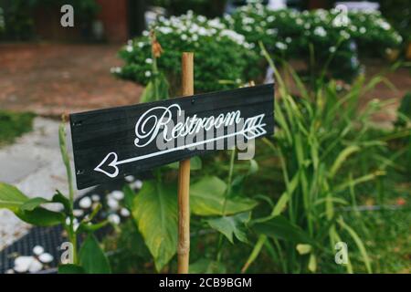 Nahaufnahme eines Hinweisschilds zur Toilette während eines Außeneinrichtes Gartenhochzeit Stockfoto