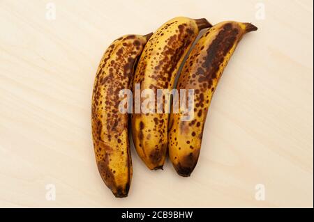 Drei reife Bananen isoliert auf hellem Holzhintergrund. Draufsicht. Speicherplatz kopieren. Stockfoto