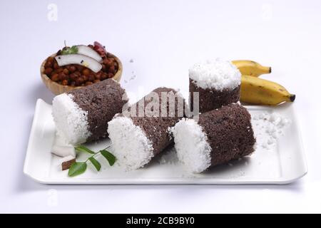 Ragi Puttu oder Millet Puttu, hausgemachtes kerala Frühstück gemacht Mit Fingerhirse und Kokosnüsse, indische Lebensmittel auf einem gelegt Weißes Geschirr mit Ka Stockfoto