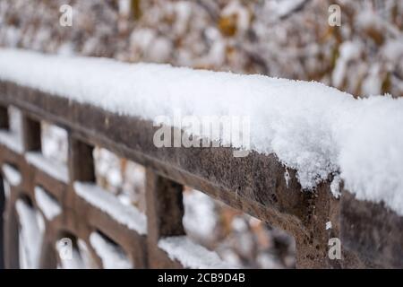 Metallgusenzaun unter dem Schnee. Fragment eines geschmiedeten Zauns mit Schnee bedeckt. Schneebedecktes dekoratives Eisengitter Stockfoto