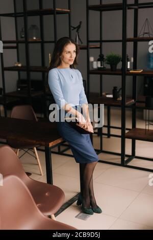 Schöne junge Geschäftsfrau hält Ordner mit wichtigen Papierdokumenten sitzen auf dem Schreibtisch. Stockfoto