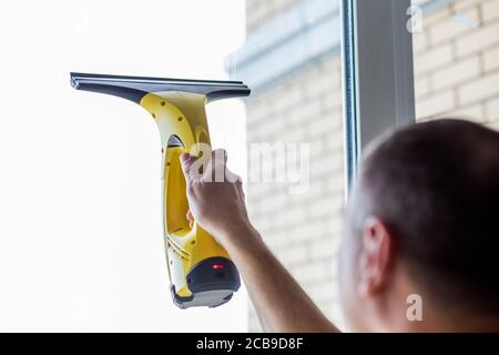 Reinigung von Fenstern mit Staubsauger.Arbeiter Reinigung Glasfenster des modernen Gebäude.Männer Hand mit tragbaren professionellen elektrischen Staubsauger. Stockfoto