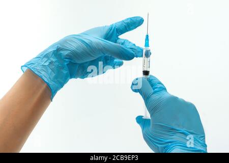 Die Hände des Arztes in blau Latex Handschuhe holding Spritze. Objekte auf weißem Hintergrund Stockfoto