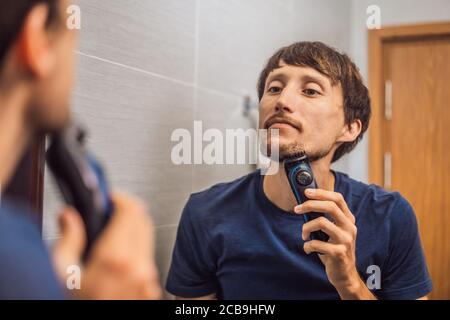 Hübscher junger bärtiger Mann trimmen seinen Bart mit einem Langhaarschneider Stockfoto